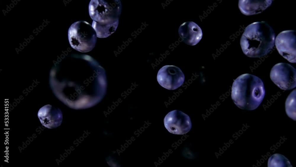 Large juicy blueberries are bouncing and rotating on the black background