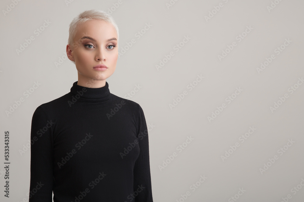 Portrait of a beautiful blonde girl with a short haircut. Grey background. Portrait of a beautiful blonde girl with a short haircut. Grey background.