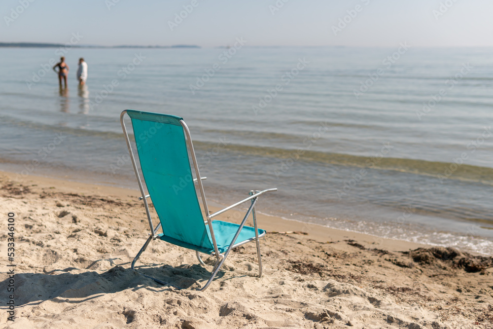 A folding chair on the beach facing the sea. Warm sunny day. Symbol of holidays, leisure. A folding chair on the beach facing the sea. Warm sunny day. Symbol of holidays, leisure.