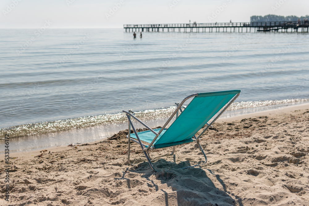 A folding chair on the beach facing the sea. Warm sunny day. Symbol of holidays, leisure. A folding chair on the beach facing the sea. Warm sunny day. Symbol of holidays, leisure.