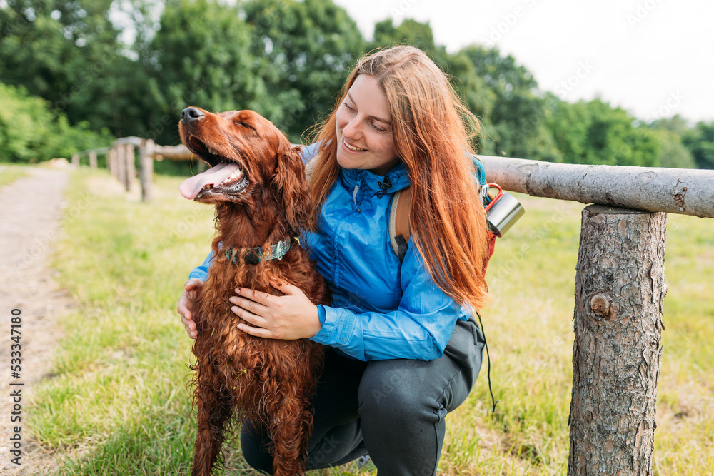 Woman and her friend dog on country road background. Human and a dog. Concept of solitude and recreation on nature with pet. Lifestyle portrait. High quality photo. Irish Red Setter Dog.