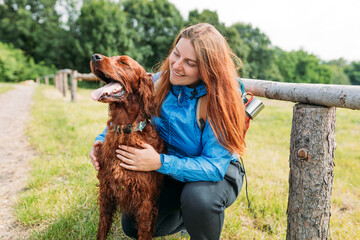 Woman and her friend dog on country road background. Human and a dog. Concept of solitude and recreation on nature with pet. Lifestyle portrait. High quality photo. Irish Red Setter Dog.