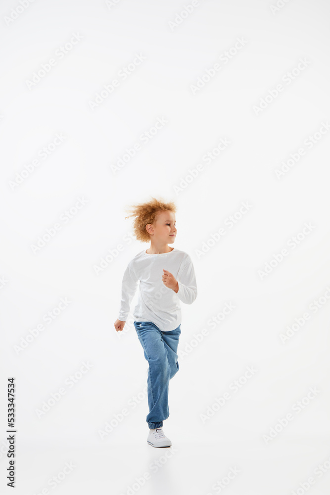 Full-length portrait of little girl, kid in white long sleeve blouse and jeans running isolated over white background. Fashion, happy childhood Full-length portrait of little girl, kid in white long sleeve blouse and jeans running isolated over white background. Fashion, happy childhood