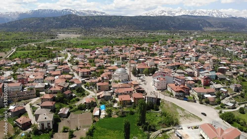 Scenic spring view from drone of Yesildag village with residential houses and mosque in green valley surrounded by mountains with peaks covered with snow, Turkey photo