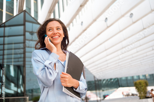 Excited caucasian businesswoman standing near office building have phone conversation feeling surprised Happy female worker happy smile after hear good news