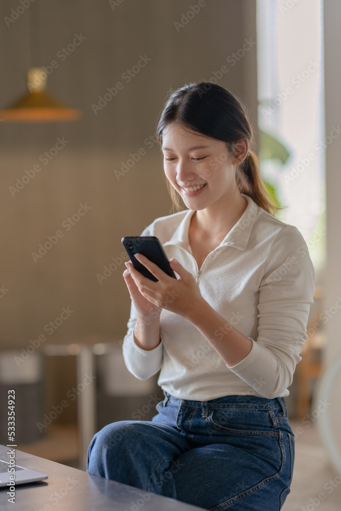 Attractive young Asian woman using mobile phone in the cafe.