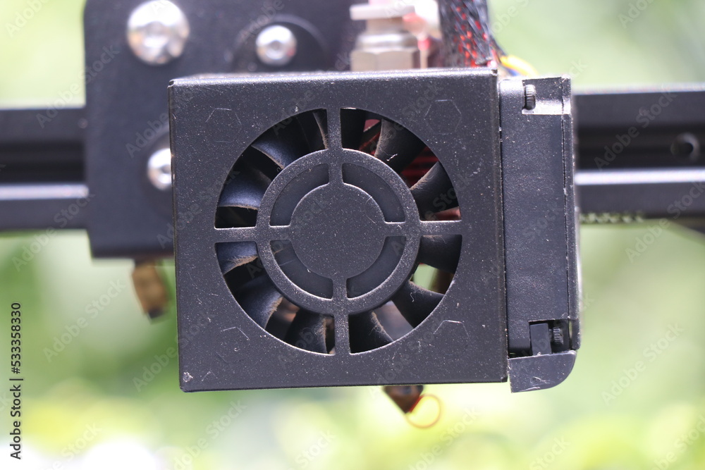 Fototapeta premium Extruder part of a 3d printer with a cooling fan on a natural light