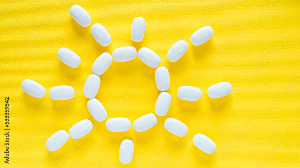 White pills on a yellow background. health care and medicine. Vitamin D. Vitamin for bright and positive emotions. Sun. White pills on a yellow background. health care and medicine. Vitamin D. Vitamin for bright and positive emotions. Sun.
