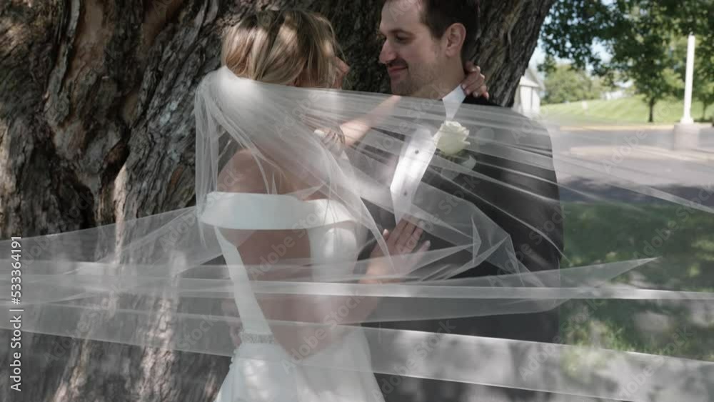 Bride and groom kissing outside with the vail blowing in the wind. Bride and groom kissing outside with the vail blowing in the wind.