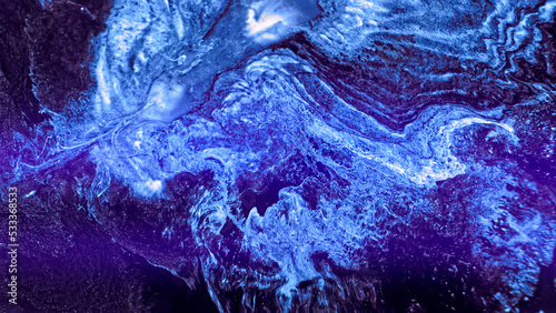 Bright blue neon paint spreads. Abstract colorful blue glowing liquid explosion over dark surface. Action particles on dark area background. Mix ink art blast. Blue flowing paint