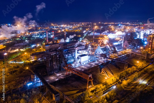 Aerial view of steel plant at night with smokestacks and fire blazing out of the pipe. Industrial panoramic landmark with blast furnance of metallurgical production. Concept of environmental pollution © ArtEvent ET