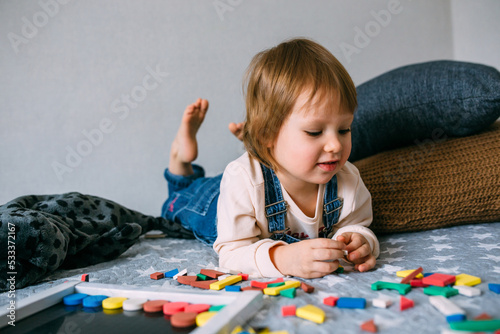 Child plays at home an educational game with a multi-colored magnetic puzzle