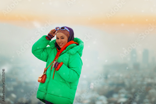 Modern woman in hijab with green jacket posing on a winter day