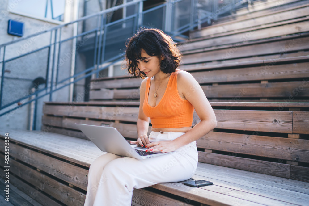 Positive young woman using laptop on stairs Positive young woman using laptop on stairs