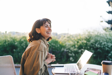 Cheerful digital nomad at table with laptop