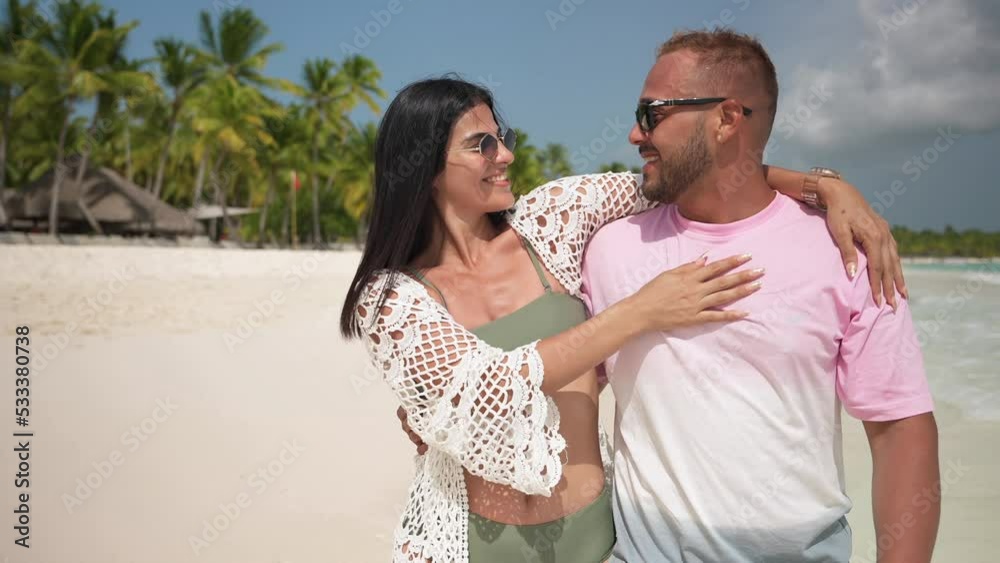 Latin american couple enjoys a vacation on the tropical beach. Turquoise water and white sand with palm trees. Slow motion shot Latin american couple enjoys a vacation on the tropical beach. Turquoise water and white sand with palm trees. Slow motion shot