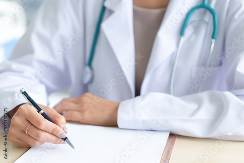 Female doctor writing on medical paper at a clinic.