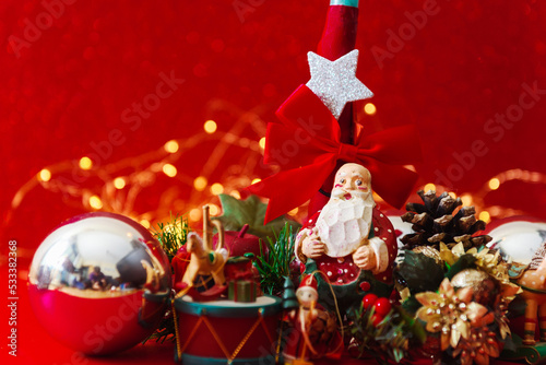 christmas greeting card with antique figure of Santa Claus among other christmas decorative objects on red background