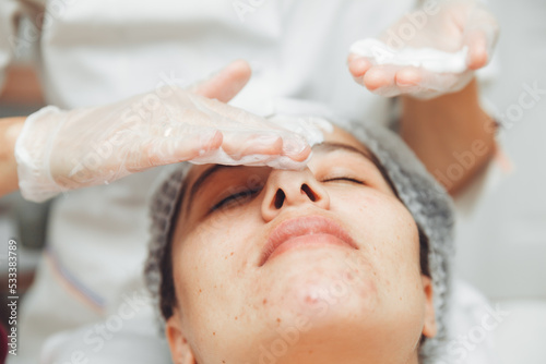 the cosmetologist cleanses the skin with foam. A woman's skin care procedure. Natural cosmetics. A beautiful face. Cosmetic treatment of the face. Therapeutic peeling cream.