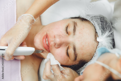 Ultrasonic cosmetic scrubber. Facial cavitation procedure. Salon skin care procedure. Professional hardware peeling. Acne removal. contaminated person
