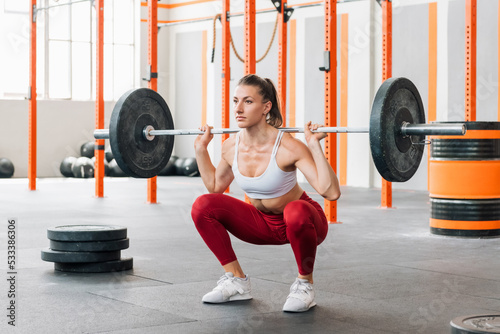 Sportswoman doing barbell back squat photo