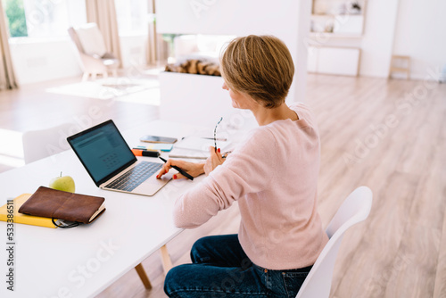 Concentrated woman freelancer browsing laptop at table in living room