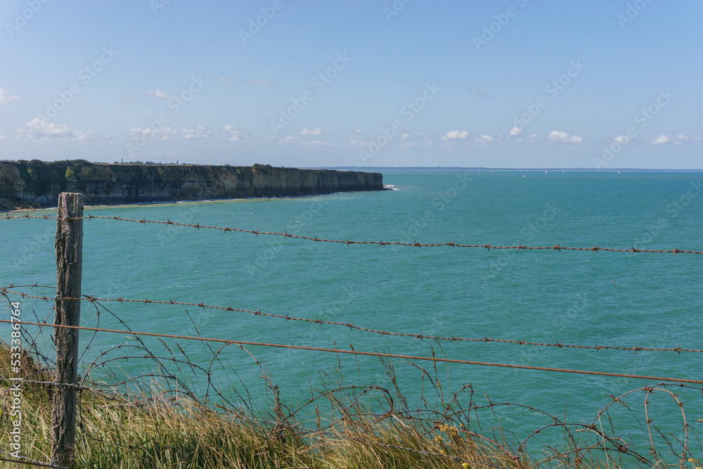 Barbed wire at the northern french coast with the sea on a sunny summer day at Pointe du Hoc, Cricqueville-en-Bessin, Normandy, France