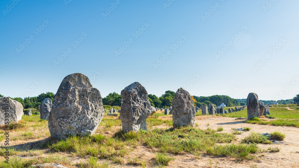 The mysterious rows of megalithes (menhir) in the archeological site of Carnac, Brittany, France. Blue sky on the background.