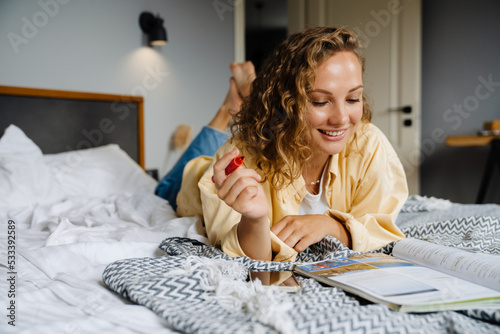 Young beautiful smiling curly woman taking notes in textbook