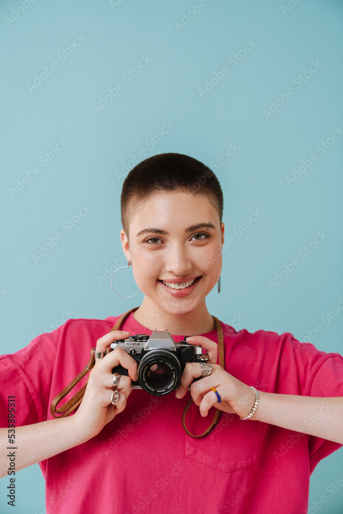 Young woman smiling while posing with retro camera