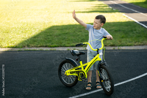 cheerful boy with bicycle waving hand, space for text, sport childhood concept 