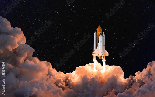 Spaceship takes off into the night sky. Rocket launch with enormous smoke cloud. Space shuttle taking off to space