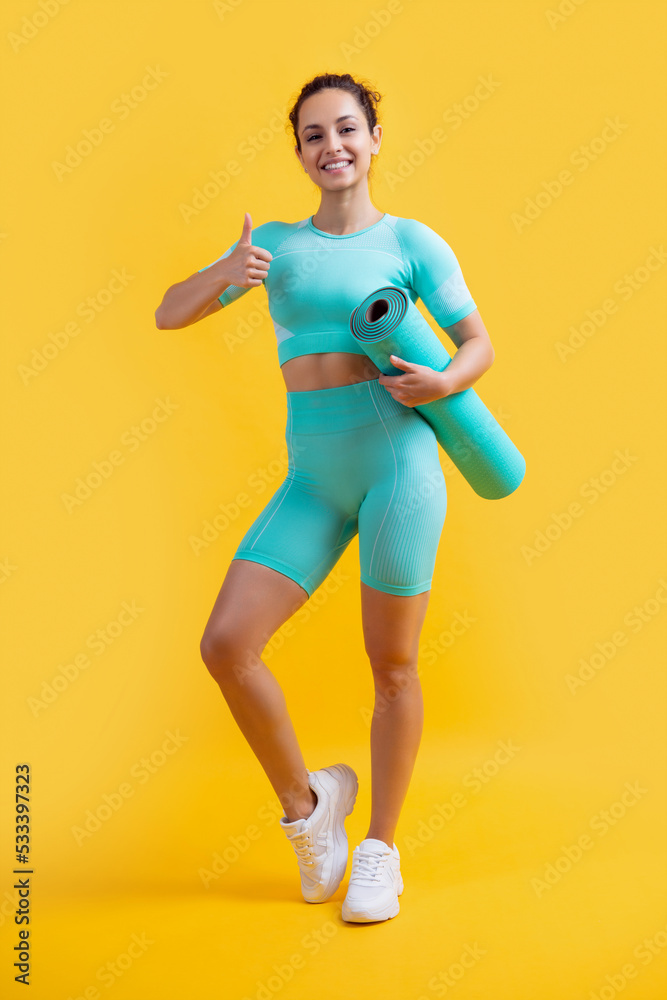 sportswoman in sportswear with fitness mat showing thumb up. fitness sportswoman in sportswear