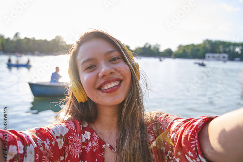 young latina taking a selfie with boats in the background. smiling tourist woman with white teeth and long hair. © Oscar