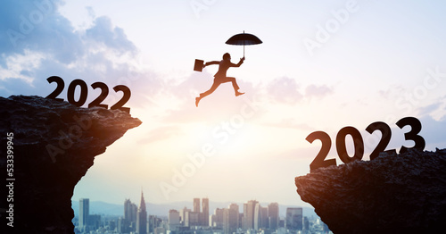2023 New Year concept. Businessman jumping over a valley.