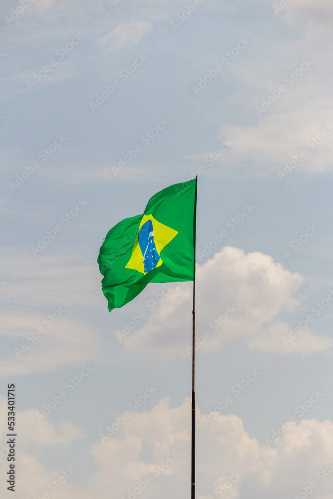 Bandeira do Brasil voando e tremulando ao vento com o céu nublado ao fundo. Bandeira do Brasil voando e tremulando ao vento com o céu nublado ao fundo.
