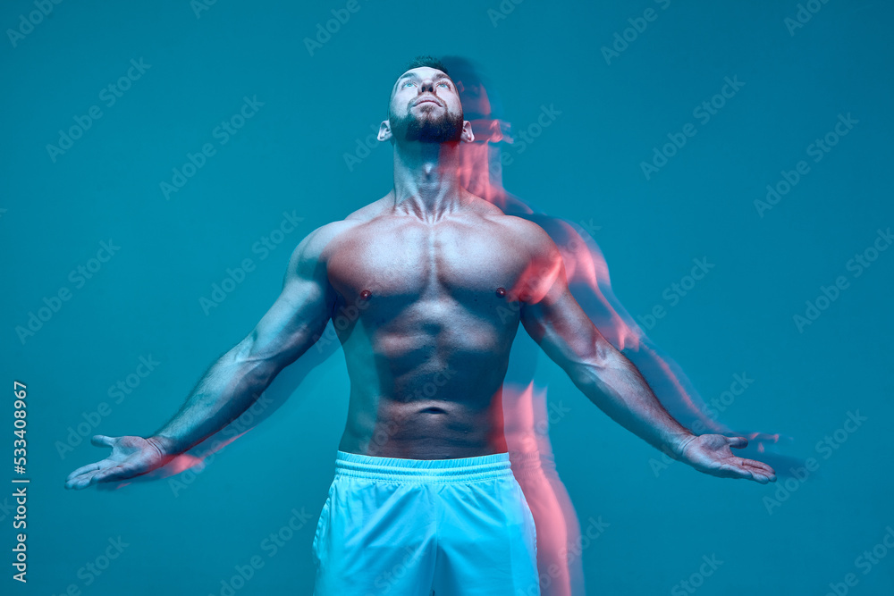 Strong powerful athlete sportive man with muscular naked body looks up. Long exposure. Neon studio light. Sport workout Strong powerful athlete sportive man with muscular naked body looks up. Long exposure. Neon studio light. Sport workout