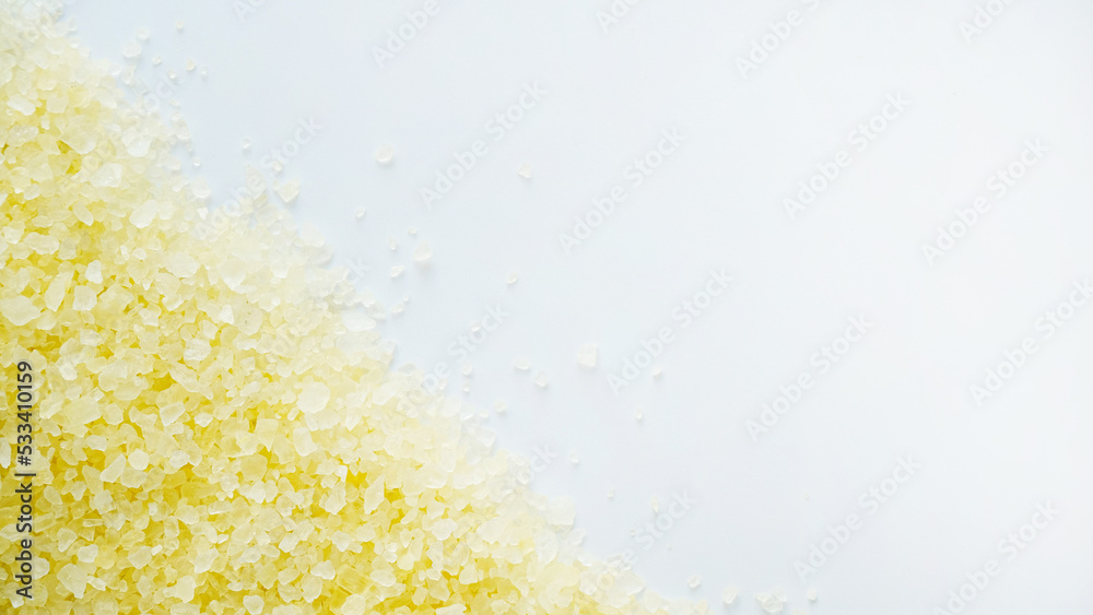 Obraz premium Texture of yellow sea salt crystals on a white background