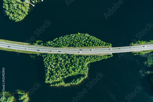 Aerial view of road through blue lakes or sea with green woods in Finland.