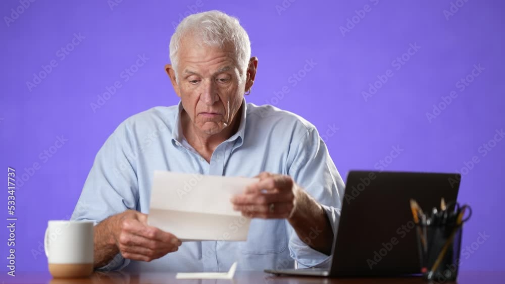 Portrait of angry stressed elderly man 70s, opening envelope reading bad news in mail letter. Mad man feels frustrated about high bills, bank debt, tax invoice or mistake isolated on purple background
