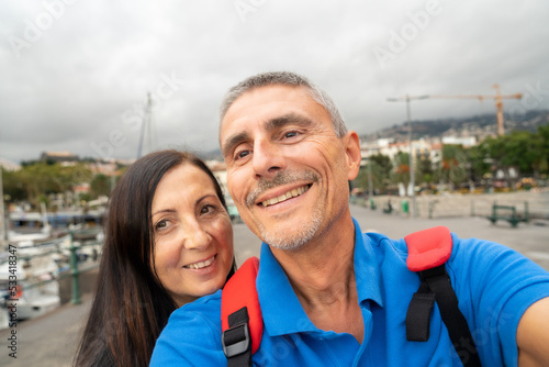 Happy couple taking selfies in a beautiful island small port © jovannig
