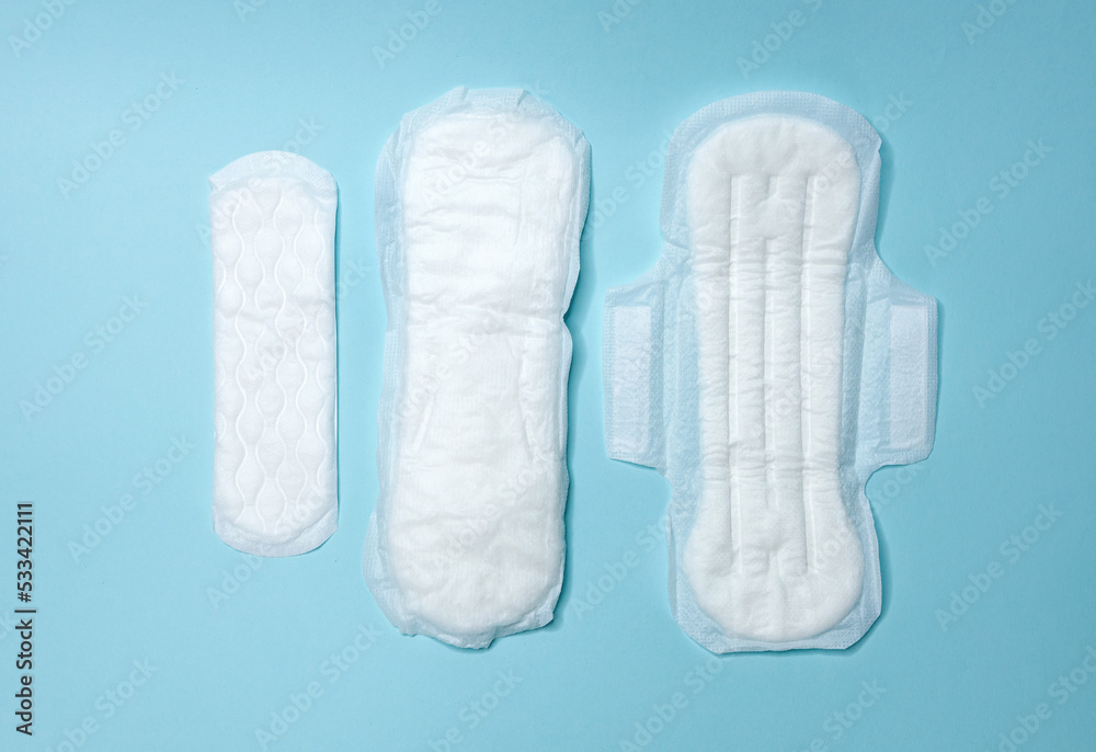 Sanitary pads are lying on a light blue background. Menstrual cycle and pregnancy. Negative pregnancy test and contraceptives Sanitary pads are lying on a light blue background. Menstrual cycle and pregnancy. Negative pregnancy test and contraceptives