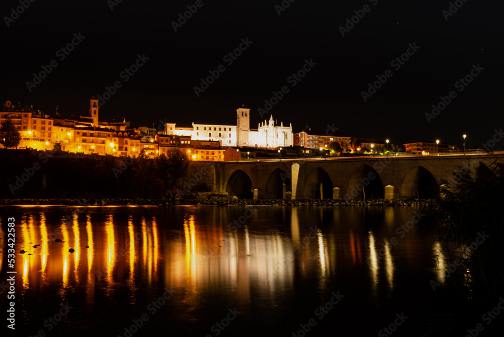 Naklejka premium Night view of a village with a stone bridge from medieval times.