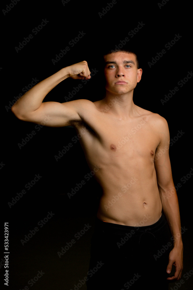 Nineteen year old teen boy flexing his arm muscles
