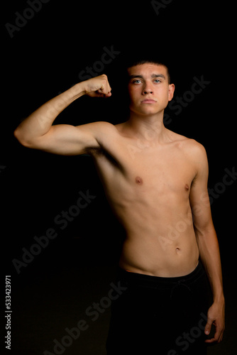Nineteen year old teen boy flexing his arm muscles