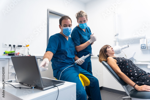 Dental clinic, dentist preparing the new scanner to make the 3d denture, explaining how it works