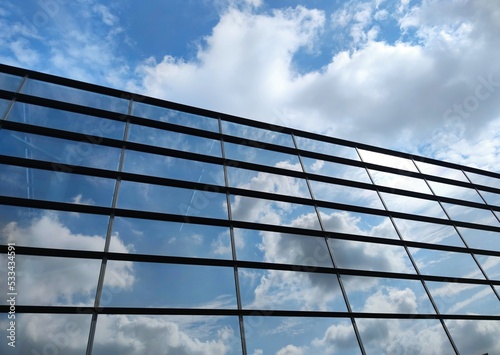 Modern futuristic glass facade of corporate finance office skyscraper business building architecture blue sky glass reflection.