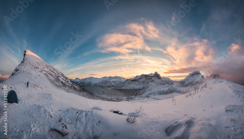 Panorama of sunrise over snowy mountain range with mountaineer tent camping in winter on Segla Mount at Senja Island © Mumemories