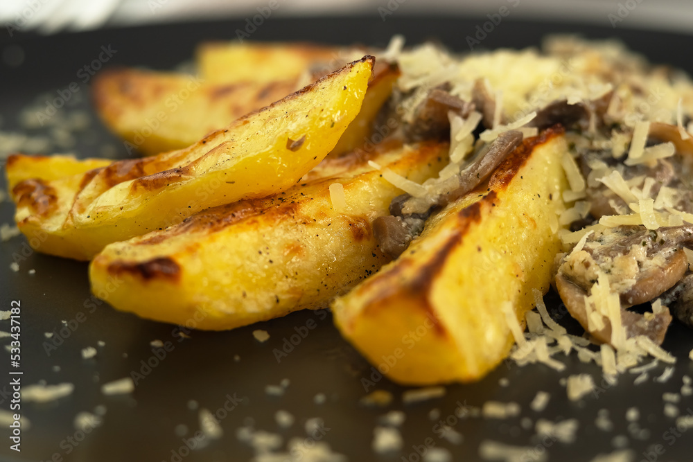 Close up of plate of baked potatoes with mushrooms sprinkled with permesan cheese. Champignons Close up of plate of baked potatoes with mushrooms sprinkled with permesan cheese. Champignons