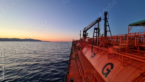 Gas tanker proceeding near the mountainous shore of the island after sunset